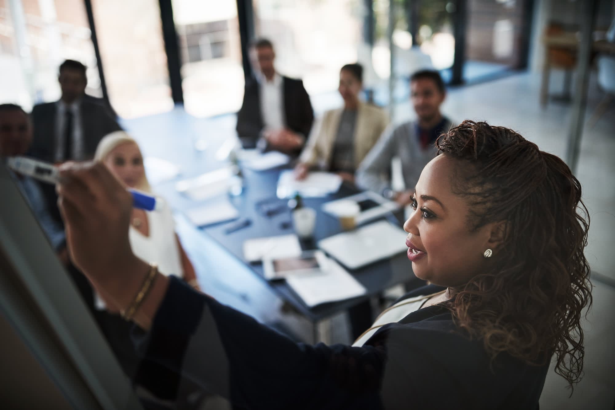 A woman leading a team meeting at a whiteboard
